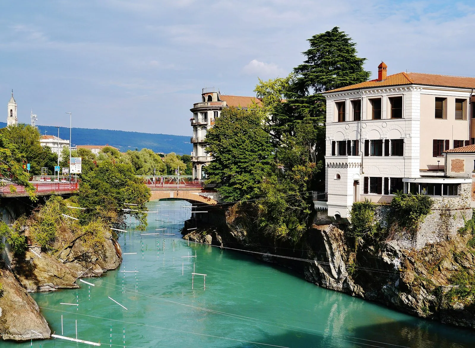 La Dora Baltea dalle acque verde smeraldo che scorre tra le rocce nel centro di Ivrea, con un ponte e i palazzi sulle sponde
