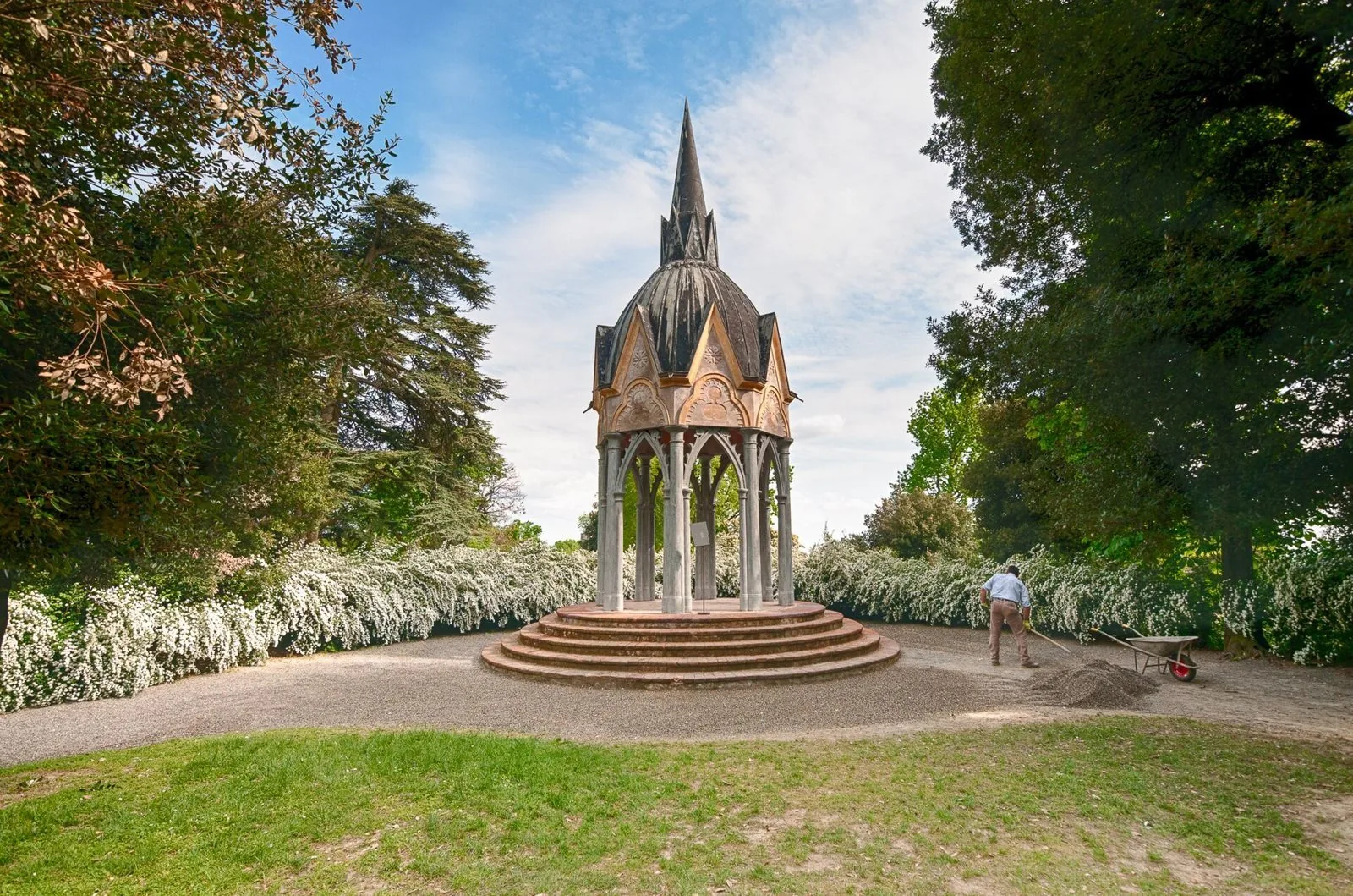 Tempietto neogotico tra siepi fiorite bianche e grandi alberi nel parco del Castello di Masino